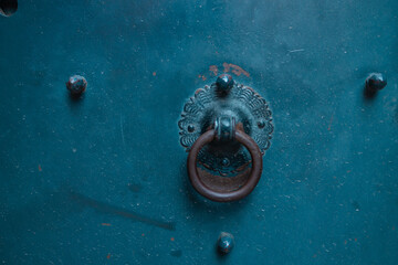 Old metal door handle knocker on a rough background. High quality photo