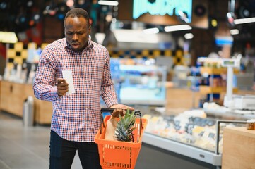 African man shopping at supermarket. Handsome guy holding shopping basket