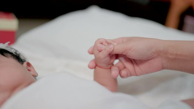Holding a newborn's hand in slow motion Happy family, mother and her newborn baby together. concept of motherhoodv