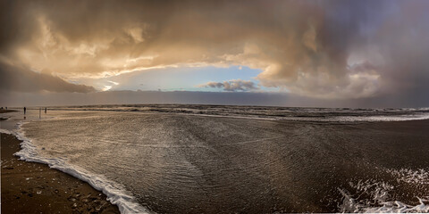 Golden sunlight, low hanging rain clouds and incoming tide during a december afternoon on the North Sea coast on the island of Rømø