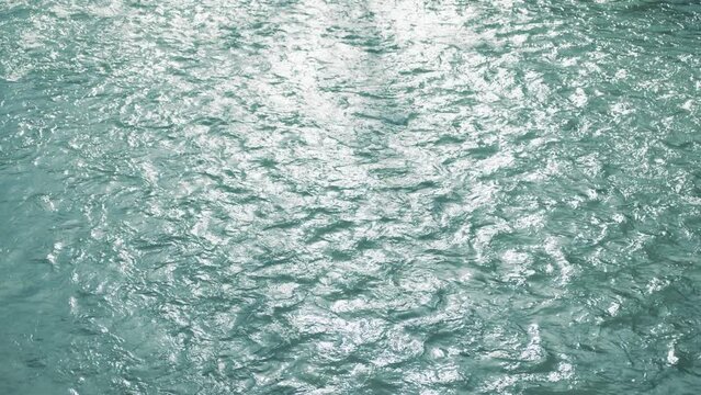Mesmerizing view of a shallow water surface of a river or lake with slack current, reflecting sun beams. Close up of calming sparkling waves moving slowly. High quality 4k footage