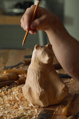 The master woodcarver begins work on the bear figure by carving it out of wood