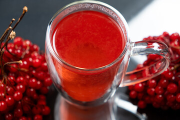 Hot viburnum tea in a glass cup with a double bottom on a black background.