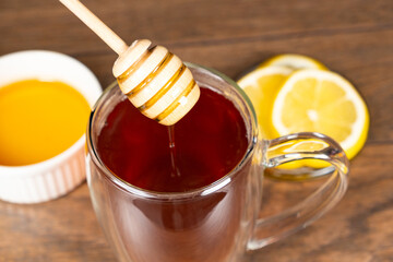 Adding honey to black tea, making vitamin healthy tea. - Powered by Adobe