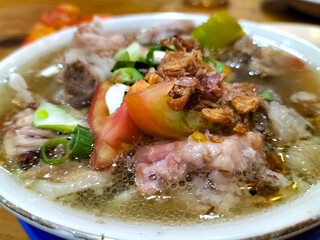 Sop kambing or Goat Soup is a mutton soup dish commonly found in Indonesia. This dish is made from mutton, tomatoes, celery, green onions and ginger. Close-up.
