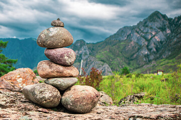 A high tower of flat stones stands on the seashore in cloudy weather - obrazy, fototapety, plakaty