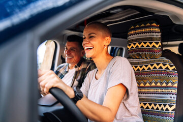 couple laughing happy during their route through the countryside in camper van, concept of adventure travel and active tourism in nature - obrazy, fototapety, plakaty