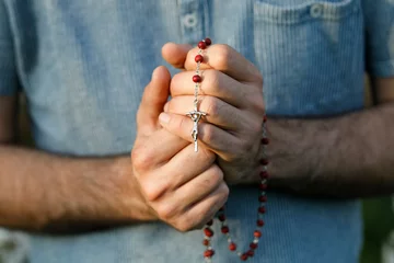 Fotobehang Young man praying with rosary in Eure, France. © Julian