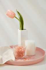 Pink himalayan salt contained inside glass cup, displayed with scented candle and a flower pot on pink tray. The coarse texture of Himalayan salt can do wonders for our bodies as a scrub