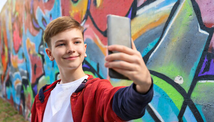 Teenage boy taking a selfie against a grafitti wall, colourful, vibrant