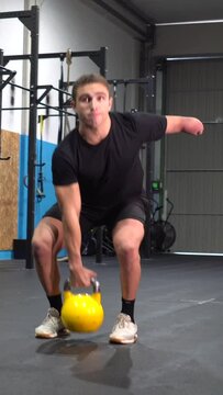 Portrait with copy space of a disabled sportive man lifting a kettlebell in a cross training gym