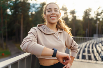Young woman in sportswear is training outdoors. Fitness woman with smart watch goes in for sports,...