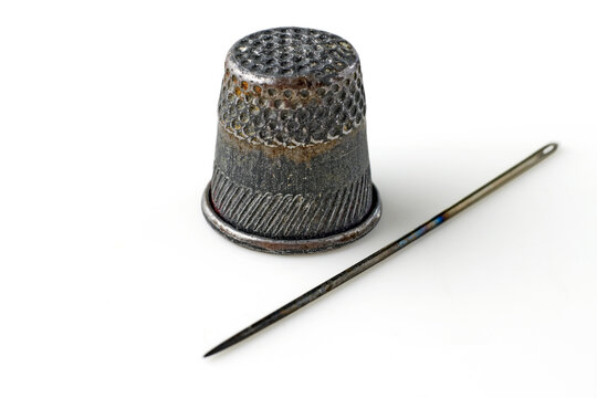 Old thimble and rusty sewing needle isolated on white background