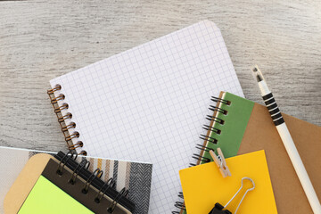 Top view of blank notepad placed near office supplies, notepad with sticky notes and on wooden table