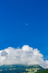 Solo paragliding in the clear blue sky over the mountains, Swiss Alps in Switzerland