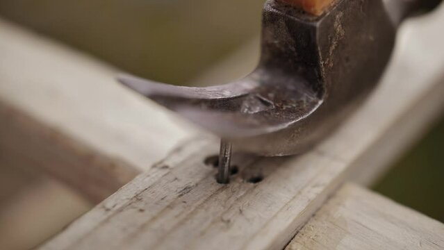 Slow motion close up of a hammer pulling a nail out of wood