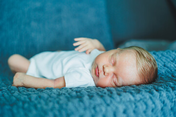 Portrait of a sleeping baby. A newborn baby is sleeping. A baby in a white cotton bodysuit