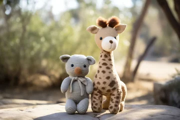 Foto op Plexiglas A small gray crocheted teddy bear and a spotted toy giraffe are walking in the park on a sunny wall. Child and eco Friendly sustainable Toy, Handmade Crochet Playtime. Copy space. © Silga