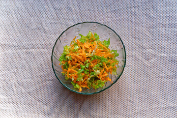 Salad prepared with curly lettuce, carrots, olive oil and lemon is ready to eat in a bowl