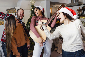 group of Latin friends singing in karaoke party celebrating christmas eve at home in Mexico Latin...