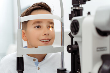 Smiling Caucasian boy receiving eye exam at clinic - obrazy, fototapety, plakaty