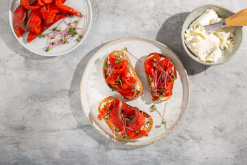 Sandwich with cream cheese, red salmon and microgreens on toasted bread. Open sandwiches on gray table. Top view.