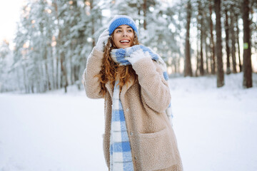 Young woman enjoys a beautiful winter day in the forest. She walks and enjoys the snow. Winter...