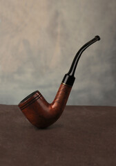 Smoking pipe on dark background. Wooden classic tabacco pipe.