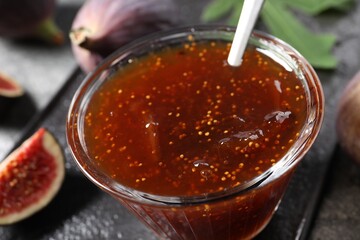 Glass bowl with tasty fig jam on table, closeup