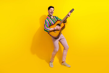 Fototapeta na wymiar Full body size photo of young model crazy man playing on guitar teaching people how to do it well isolated over yellow color background