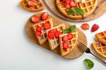Tasty Belgian waffles with strawberries, mint and fork on white table, flat lay
