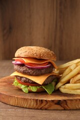 Delicious burger with meat cutlets and french fries on wooden table, space for text