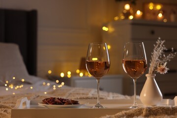 Tray with glasses of wine on bed, space for text. Romantic evening