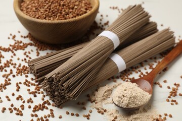 Uncooked buckwheat noodles (soba), flour and grains on white table