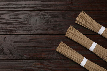 Uncooked buckwheat noodles (soba) on wooden table, flat lay. Space for text