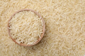 Bowl and raw rice as background, top view. Space for text
