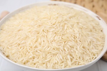 Raw rice in bowl on table, closeup