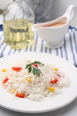 Plate of delicious rice with vegetables and parsley on table, closeup