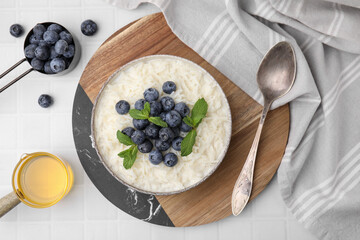 Bowl of delicious rice porridge with blueberries and mint served on table, flat lay