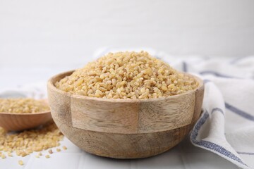 Raw bulgur in bowl on table, closeup