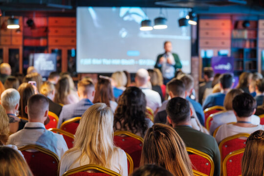Back view of diverse businesspeople attending global workshop in conference hall at forum