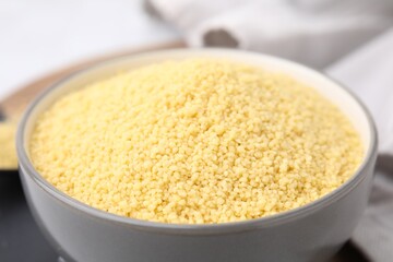 Raw couscous in bowl on table, closeup