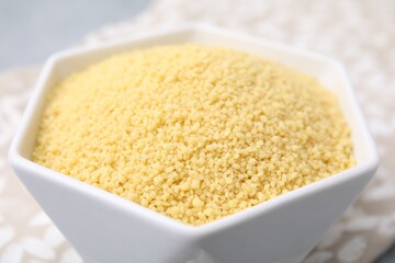 Raw couscous in bowl on table, closeup