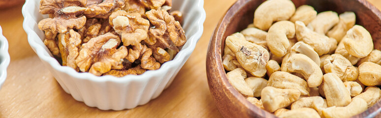 top view of high-calorie cashews and walnuts in bowls on table, plants-based diets concept, banner