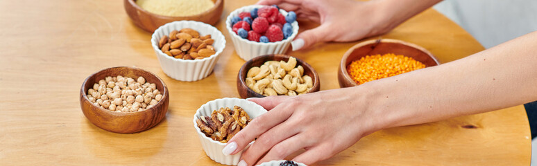 cropped view of woman arranging bowls with various and wholesome plant-based food on table, banner