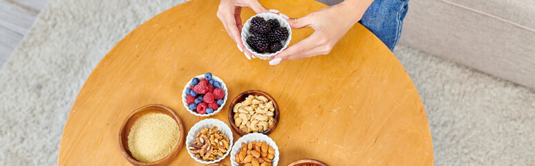 top view of woman with fresh blackberries near various plant-based products on table at home, banner