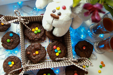 Chocolate muffins. Sweet dark cookies with chocolate and cocoa powder.. Homemade, freshly baked delicious cupcakes on the light background with garland
