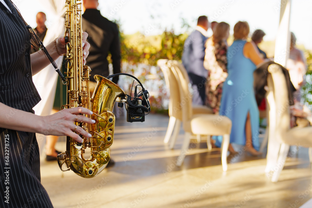 Wall mural a woman musician plays the saxophone at an open-air party.