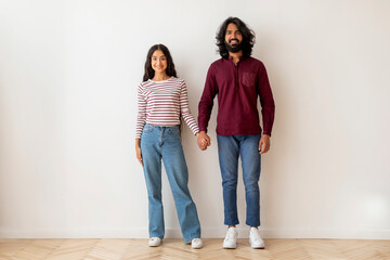 Positive young indian man and woman posing over white wall