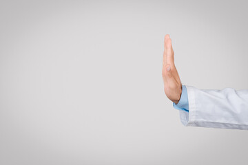 Male doctor in white coat with stop gesture, side view, grey background, free space